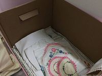 Box with embroidered linens and doilies with colorful floral embroidery and lace detailing