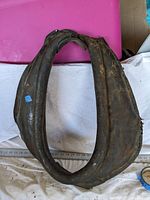 Photo showing front view of the antique horse collar bridal laid flat, highlighting the worn leather and size.