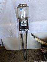 Full view of the vintage Beaver gumball machine with clear glass container and metal coin-operated base on long metal legs.