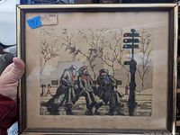 Framed lithograph titled "Paris - Sur le Banc" by Marcel Harang showing three figures on a bench in Paris with trees and street sign, under glass with slight reflections.