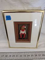 Framed artwork showing a small bear in red and white polka-dot costume in a gold-tone frame with decorative mats.