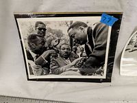 Photo of vintage press photo showing Martin Luther King Jr. talking with several men, all formally dressed, scene outdoors, photo shows slight edge wear.