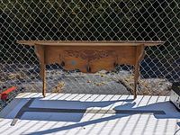 Full front view of the wooden wall shelf showing the carved design, three hooks, and the shelf surface.