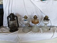 Four vintage glass oil lamps, three electrified with cords and plugs, one dark metal chimney lantern oil lamp.