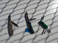Photo showing three vintage folding knives with blades partially open. Two larger knives have brown and green handles, one smaller green multi-tool knife.