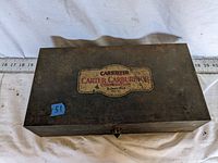 Top view of vintage metal box with Carter Carburetor Corporation label visible, showing wear and age.