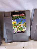 Close-up of Teenage Mutant Ninja Turtles NES cartridge game showing label artwork and condition.
