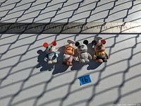 Four Disney Vinylmation figures on white background with ruler indicating size approximately 3 inches tall.