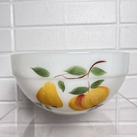 Side view of the milk glass bowl featuring hand-painted yellow and orange pears with green leaves on white glass.