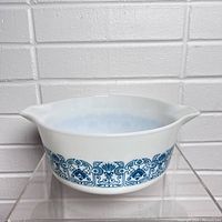Side view of the Pyrex Blue Horizon bowl showing the blue decorative band around the white glass body and the dual pouring spouts.