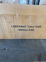 Closed cardboard box labeled 'BED FRAME SKU: PHO-0XMX8E1'.
