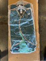 Four green Disney Frozen Anna costumes folded, new in plastic packaging.