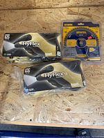 Two unopened boxes of Ansell HyFlex gloves and Irwin saw blade on plywood surface.