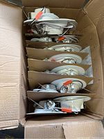 Photo of 16 stacked white smooth trim Sunco 5/6 inch LED retrofit recessed lighting fixtures showing electrical wiring and mounting springs inside a cardboard box.
