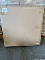 Sealed cardboard box containing the photo light box and backdrops, taped shut, with visible barcode and shipping label.
