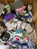 Wide angle showing assortment of random store ready merchandise including brushes, packaging, and textiles inside a wooden bin.