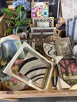 Various framed wall art, some featuring floral themes and inspirational quotes, small artificial potted plant, and several picture frames