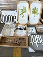 Photo showing all 10 wall decor items arranged on floor, including framed botanical prints, inspirational quote signs, and wooden word and spoon decorative pieces.
