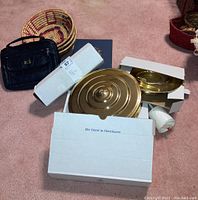 Photo showing brass communion trays, some white ceramic communion cups with a red cross, boxes, a dark blue Bible, and woven baskets on the floor.