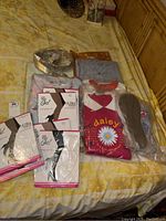 Lot items arranged on bed: unopened sheer stockings in packages, folded pajamas, belt, and tops, all size 2X.