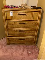 Front view of wooden chest of drawers with bamboo style frame and four drawers, showing natural wood grain and woven bamboo pattern on the top drawer.