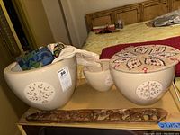 Wide view showing three ceramic planters with carved tree designs and the carved wooden piece beneath them.