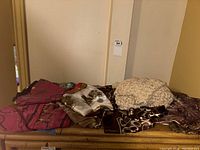 Photo of all six scarves folded and stacked on a wooden surface, showing variety of colors and prints