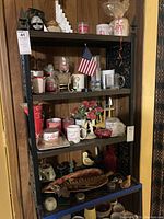 Full view of shelf with various mugs, ashtray, figurines, and glassware.