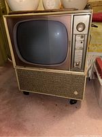 Front angled view of the vintage GE console TV showing the screen, control panel, and woven speaker grille.