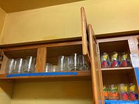 Top shelf wooden cabinet with plain clear glasses and monogrammed pieces visible