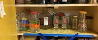 Shelf displaying various vintage glassware including pitchers, milk jugs, mugs, and jars.