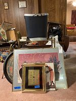 Framed prints and clock arranged in front of shelving with storage bin on top.