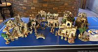 Wide shot showing multiple ceramic houses arranged in a nativity village layout with various nativity and village figures in front.