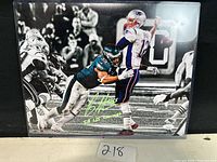 Front view of the signed photo with Brandon Graham attempting a sack on Tom Brady during Super Bowl LII. Signature and inscription visible in green ink.