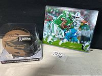 Photo of Eagles mini helmet in plastic display case with signature and NFL Salute to Service label, alongside signed football photo featuring Eagles player in action.