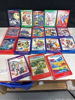 Photo shows eighteen boxed Intellivision games arrayed on a table in three rows, each with colorful illustrated covers and labeled with titles such as Space Armada, Snafu, BurgerTime, Royal Dealer, Poker & Blackjack, Space Battle, Checkers, Boxing, Backgammon, NBA Basketball, Night Stalker, Triple Action, Skiing, Lock 'N Chase, Reversi, Armor Battle, Sharp Shot, and Chess. Boxes appear dusty and aged.