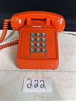 Front view of the orange telephone showing numeric keypad and handset cradle