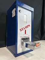 Blue metal vintage stamp vending machine with coin slot and lever showing 50 cent price