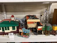 Overview of model train station buildings and assorted accessories on a shelf.