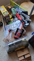 Photo of the lot items displayed in box, including air compressor, car care gift pack, adhesive tiles, lantern, flashlights, tape measure, level, hook hardware
