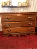 Front view of the Bassett dresser showing three drawers with brass handles and the wood grain finish.