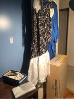 Photo of hanging dresses showing white wedding dress with black floral pattern and blue evening dress.