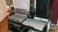 Sony CD/DVD player and Pioneer receiver on a black TV stand, along with a Brooksonic VCR below them.