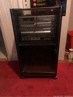 Full view of the Fisher stereo system in a wooden cabinet, featuring electronic components on top and black glass doors below.