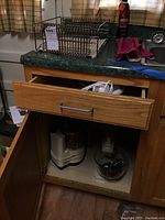 Image showing a wooden cabinet with the Regal La Machine food processor and attachments inside, with a dish drying rack on top.
