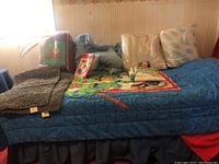 Wide view of bed with TMNT quilt, pillows, rugs, and blankets arranged