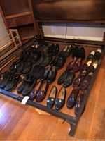 View of all shoes arranged on a metal frame, showing a variety of men's dress shoes including black, brown, and burgundy colors, polished leather loafers and derby styles, plus a wooden shoe stretcher.
