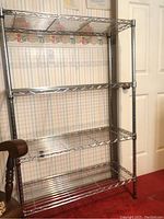 Full front view of the chrome metal wire storage rack showing four wire shelves and tubular legs.