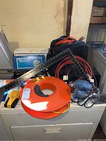 Overview of lot items including cordless drill bag, socket set case, corner square, measuring tape reel, and palm sander on top of appliance.