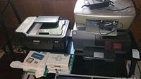 Photo showing three printers (Lexmark, HP PSC-1610, HP Officejet Pro 6830) grouped with packages of printer paper